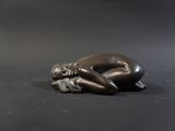 statue of a woman laying on her stomach on a black surface
