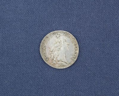 un gros plan d'une pièce d'argent posée sur un tissu bleu