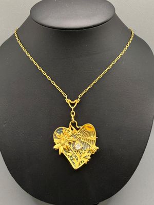 a gold necklace with a heart shaped pendant on a mannequin