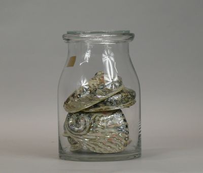 a glass jar filled with coins and shells on a table