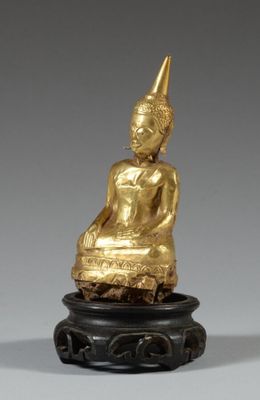 une image représentant une statue en or d'une personne assise sur un socle noir