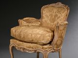 un fauteuil rembourré dont l'assise est recouverte d'un tissu doré
