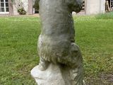 a statue of a bear on a rock in front of a house