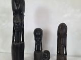 trois sculptures en bois représentant une femme, un homme et un enfant