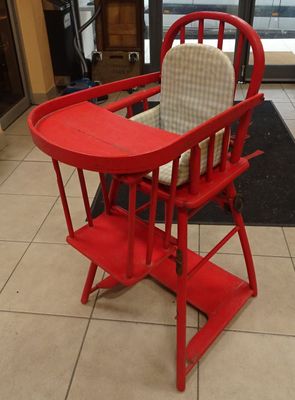 a red high chair that is in the middle of a tiled floor