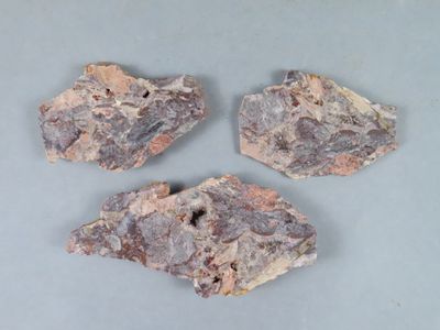 trois morceaux de roche posés sur une table, sur fond gris