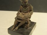 a small statue of a boy sitting on a block