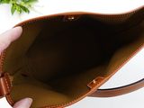 a person holding a brown purse with a plant in the background