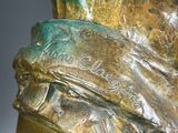 a bronze statue of a man with a hat on it ' s head