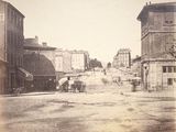 une vieille photo représentant un cheval et une calèche dans une rue de la ville