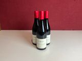 two bottles of wine sit on a table in front of a red wall