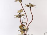 une photo d'une sculpture métallique représentant des fleurs, posée sur un socle en bois