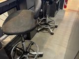 two black stools sitting in front of a computer desk