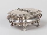 an antique silver plate with a lid on a stand on a white surface