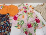 three dresses and a shirt on a white table