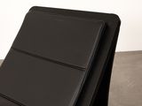 the back of a black leather chair sitting on top of a cement floor