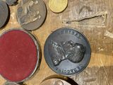 many coins on a wooden table with a coin in front of them
