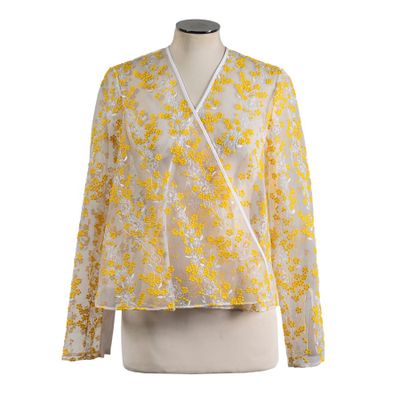 a woman ' s blouse with yellow flowers on a mannequin torso