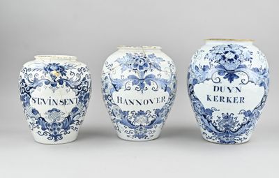trois vases bleus et blancs posés les uns à côté des autres sur une table