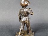 an antique bronze figurine of a boy holding a baseball bat