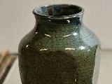 a small green vase sitting on a glass table