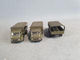 three toy army trucks are lined up on a white surface