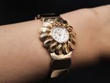a woman ' s wrist that has a gold watch on it