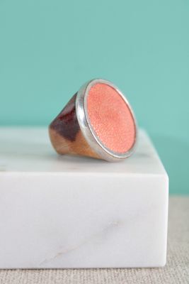 une image représentant une bague rose posée sur un bloc de marbre blanc