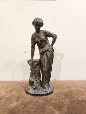 statue en bronze représentant une femme accompagnée d'un chien, posée sur un socle