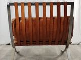 the back of a brown leather chair with a metal frame