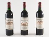 three bottles of red wine are lined up on a white surface