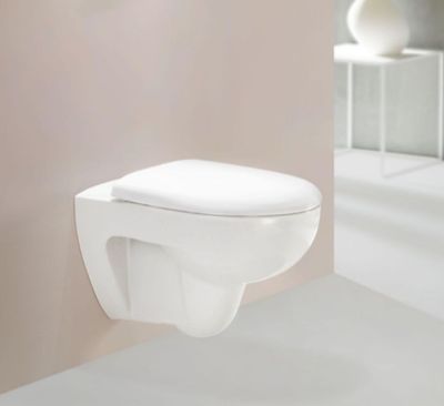 des toilettes blanches situées dans une salle de bains, à côté d'un miroir