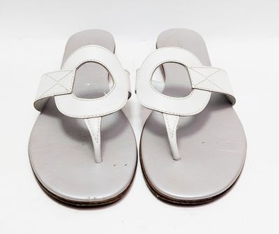 une paire de tongs blanches posées sur une surface blanche, avec un fond blanc