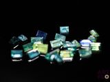 many pieces of green and blue glass on a black surface