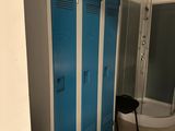 un casier bleu dans une salle de bains, à côté d'une douche