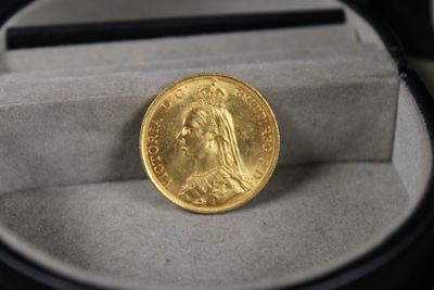 une pièce d'or dans une boîte avec une loupe