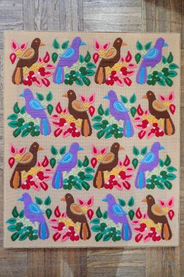 un gros plan d'un tapis orné d'oiseaux et de fleurs