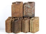 several old rusty metal jerry cans stacked on top of each other