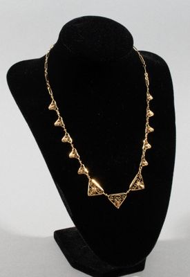 a black mannequin with a gold necklace on it