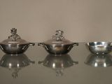 trois plats en argent posés sur une table en verre