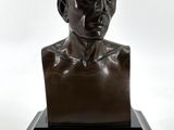 un buste en bronze représentant un homme, posé sur un socle noir