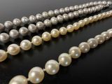 three strands of pearls are arranged on a black surface