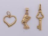 three gold charms with a heart, key, and an egyptian head