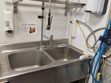 a stainless steel sink and a washing machine in a small room