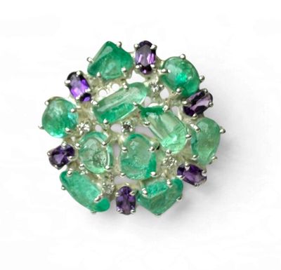 un gros plan d'une broche verte et violette posée sur une surface blanche