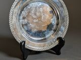 a silver plate that is on a stand on a table