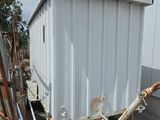 un conteneur blanc posé contre le mur d'un immeuble