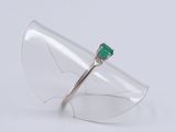 a close up of a ring with a green stone on top of a clear glass