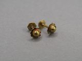 une paire de petites boucles d'oreilles en or sur une surface grise