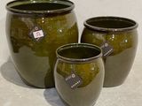 trois vases verts posés les uns à côté des autres sur une table